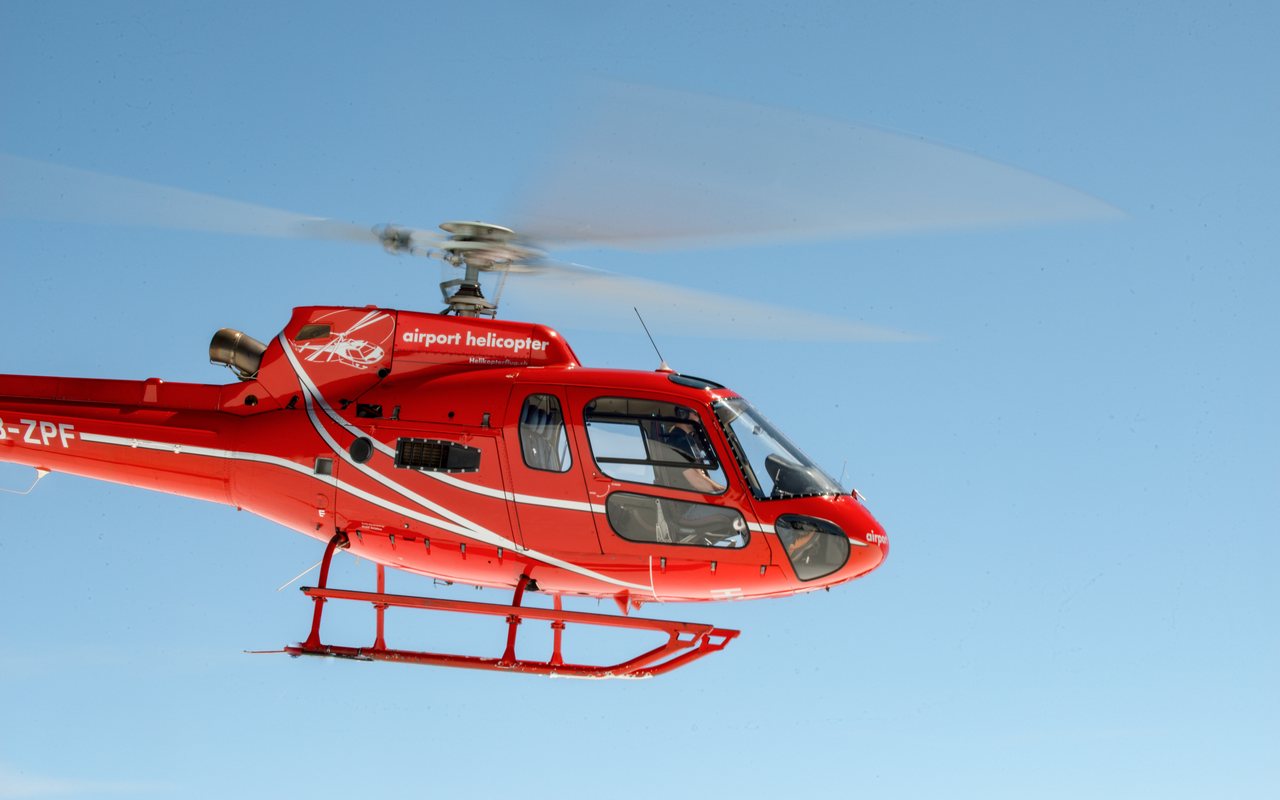 Roter Ecureuil AS350 der Airport Helicopter AHB AG im Flug