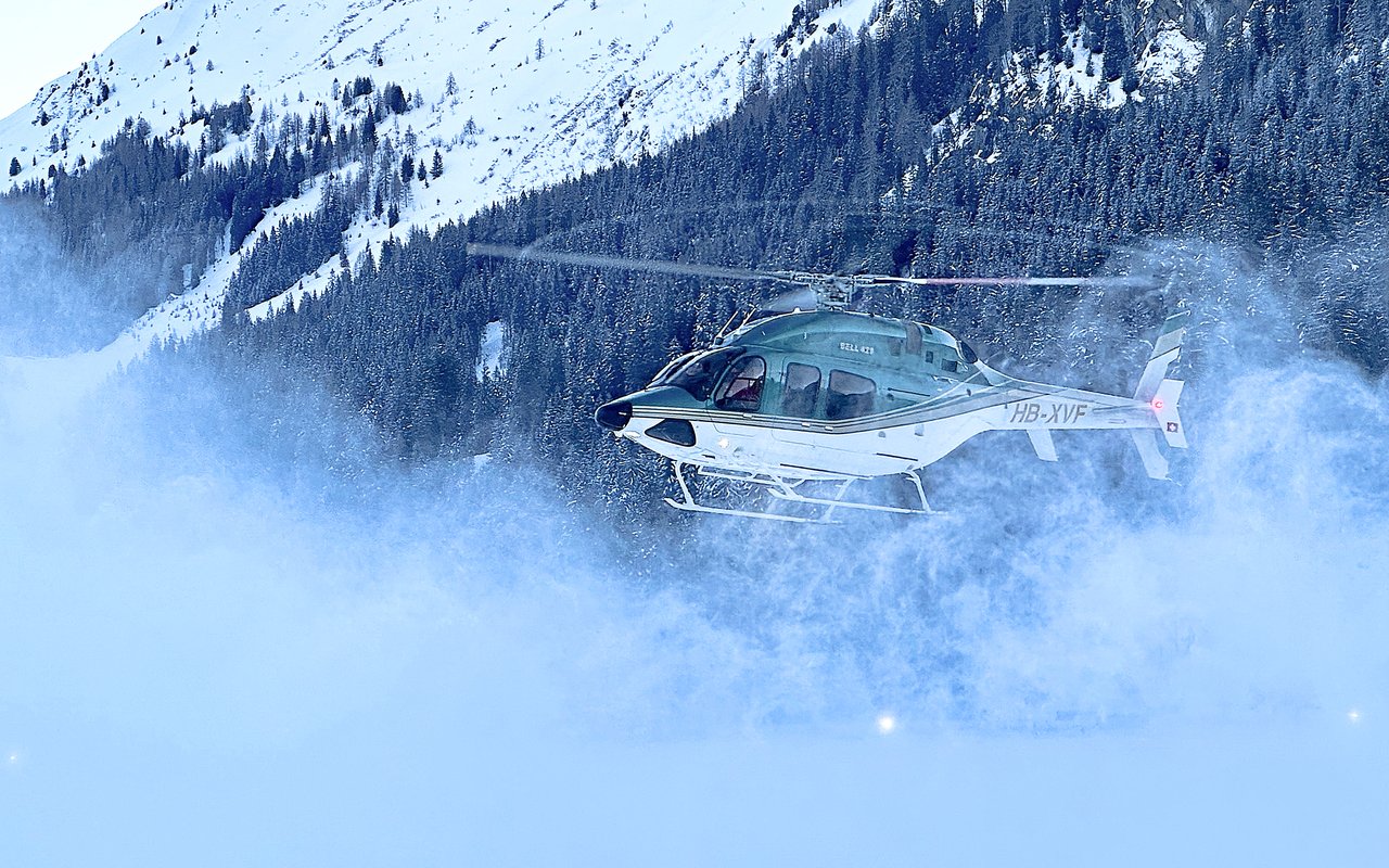 Bell 429 HB-XVF der Airport Helicopter AHB AG im Schwebeflug über einem verschneiten Hang