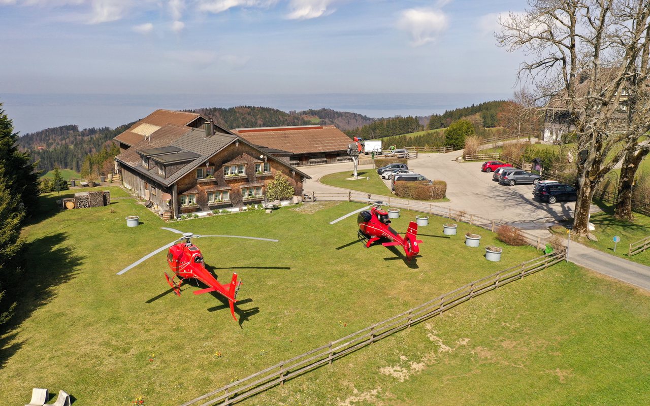 Zwei Helikopter der Airport Helicopter AHB AG vor einem Berggasthaus