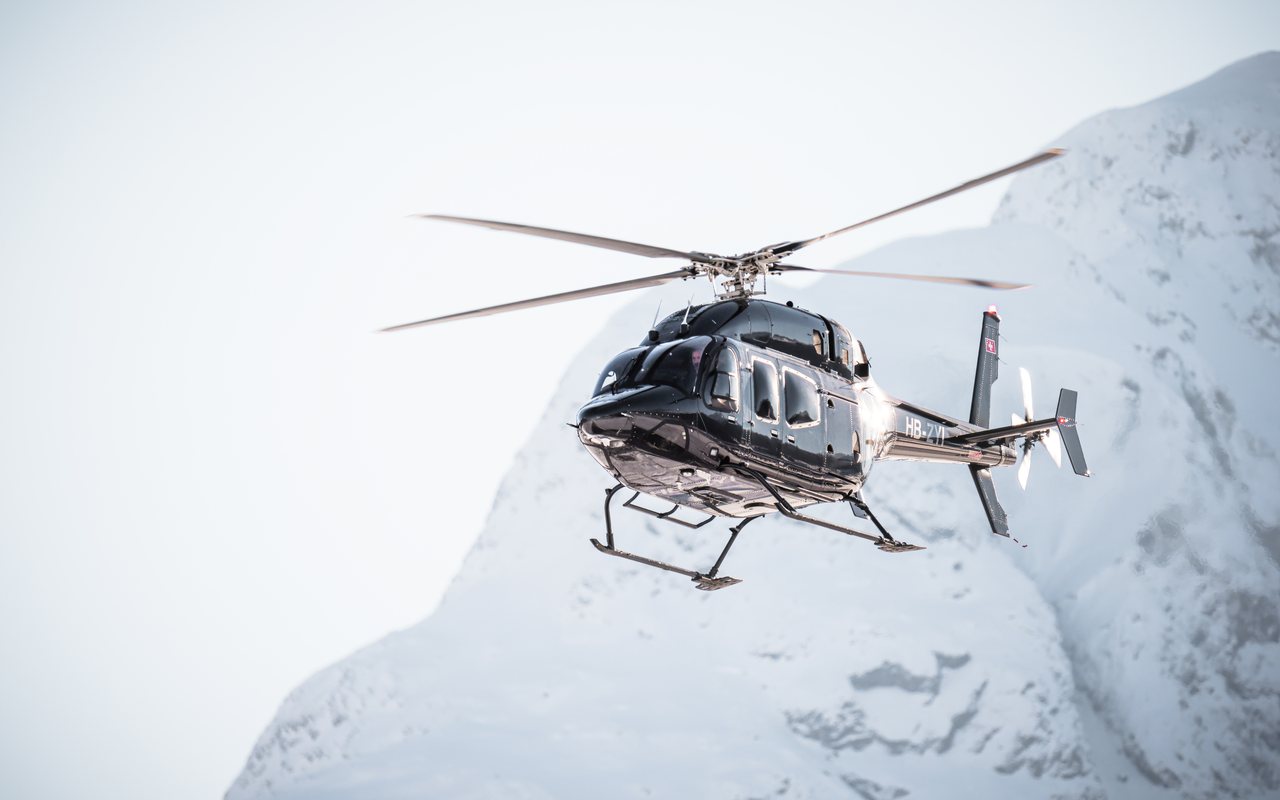 Bell 429 der Airport Helicopter AHB AG im Flug vor einer verschneiten Bergflanke